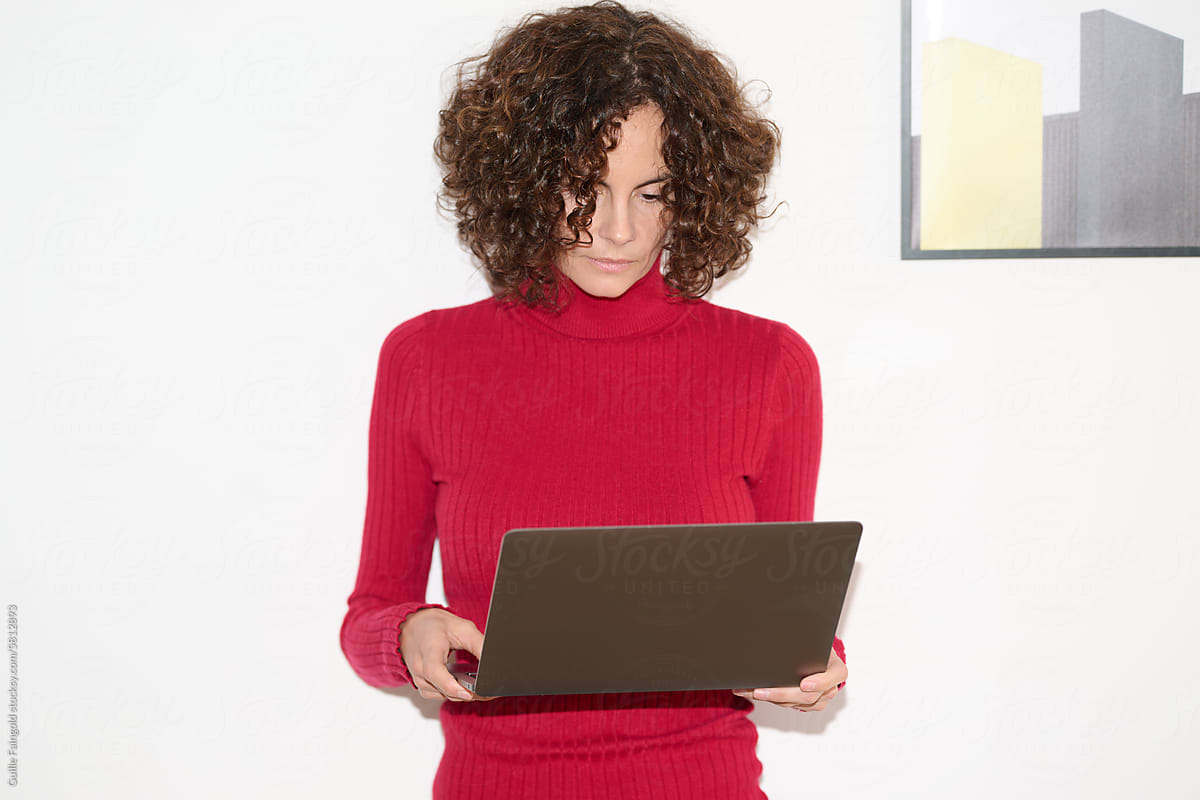 Focused Curly-Haired Woman with Laptop