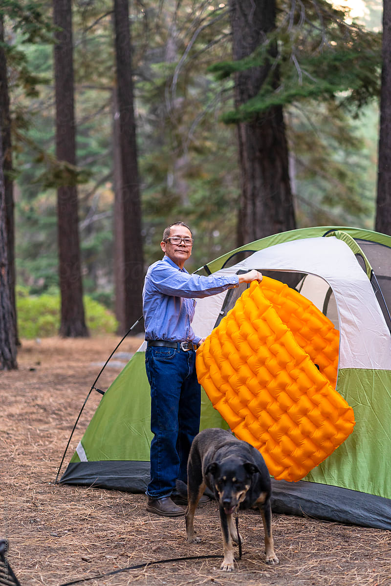 Man and dog setting up camping tent and sleeping pad
