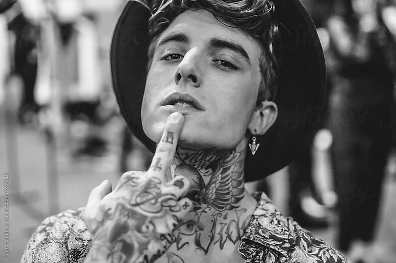 midle finger,attitude, fashionable tattooed boy with a black hat