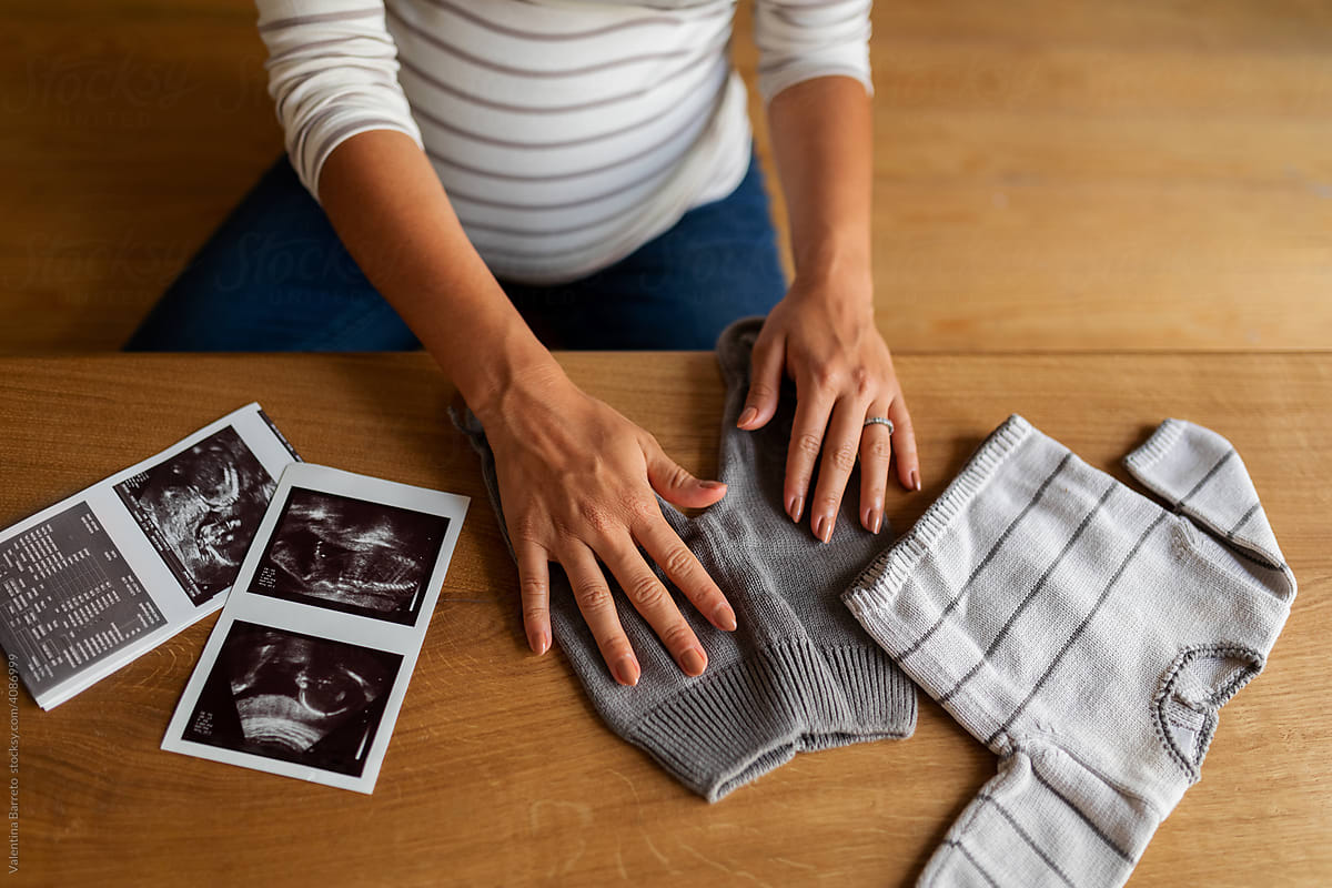 Pregnancy, baby clothes and printed ultrasounds