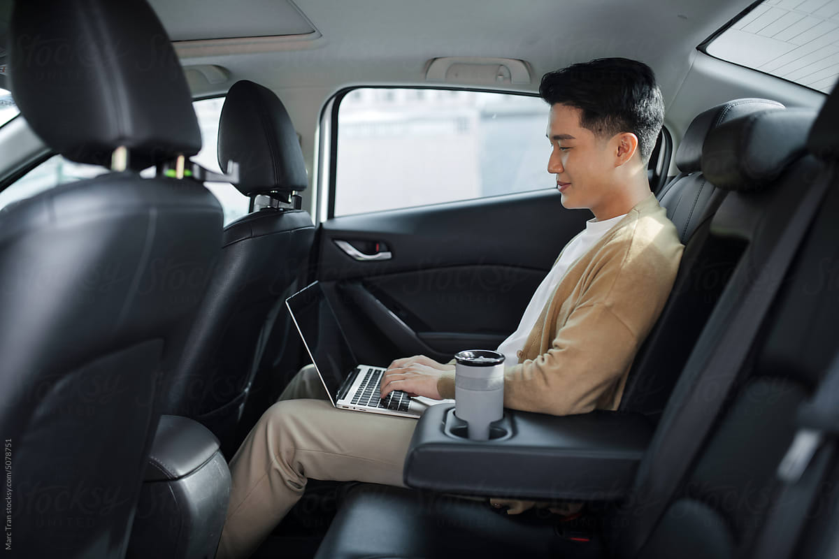 Successful young man using laptop while sitting in car
