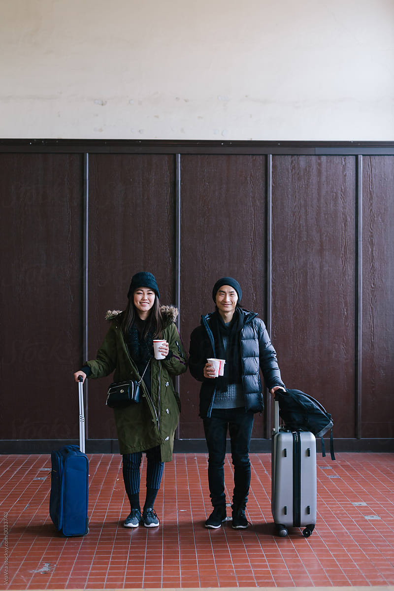 Beautiful Asian couple posing with suitcases
