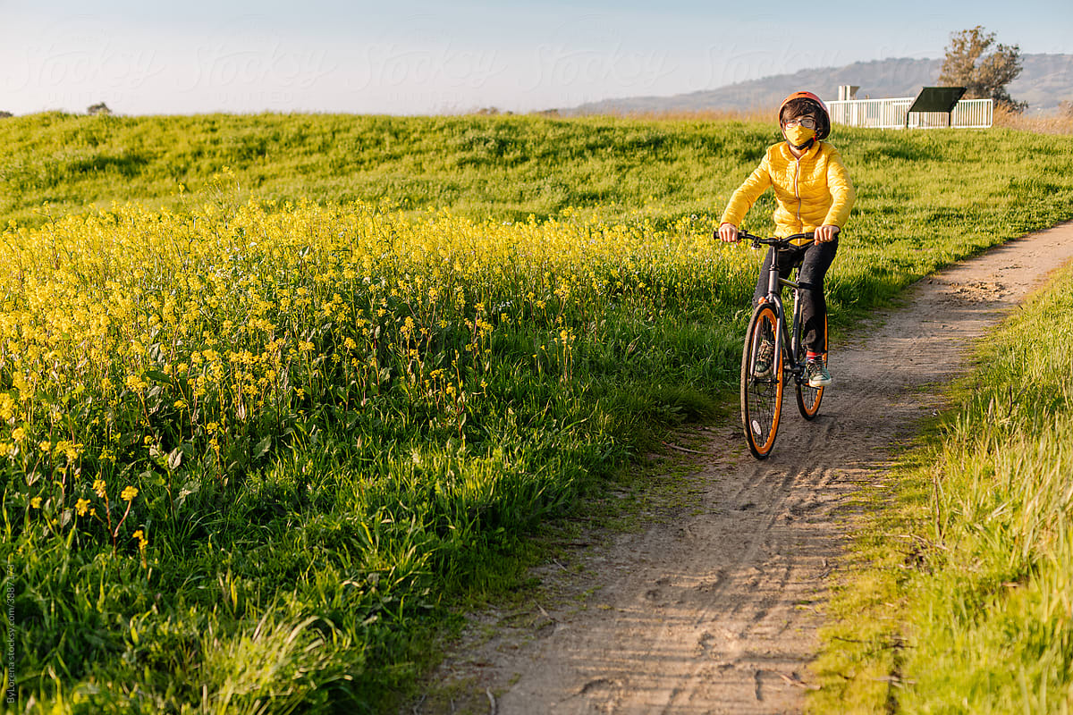 Teen boy riding bicycle along blooming meadow