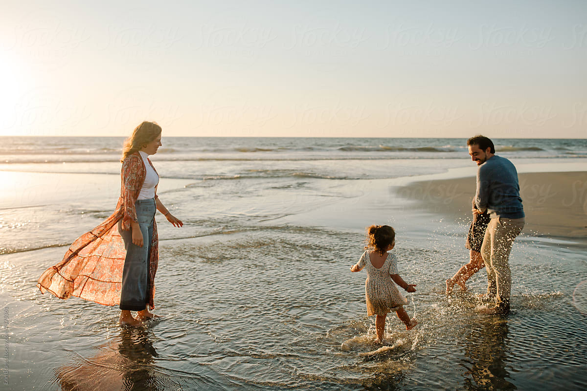 Loving family playing in ocean at sunset