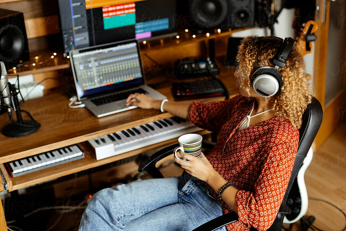 Audio producer at home studio listens to music track and drinks coffee