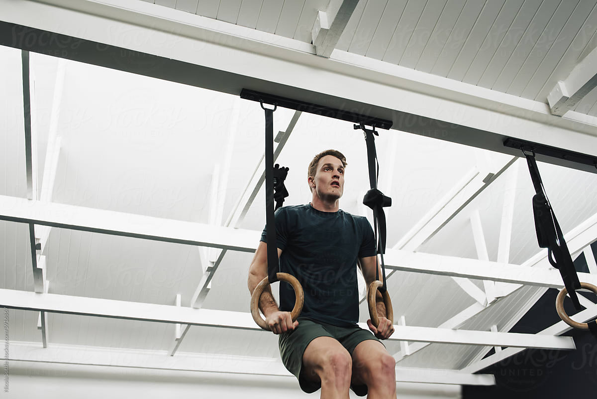 Strong man working out with rings on suspension straps