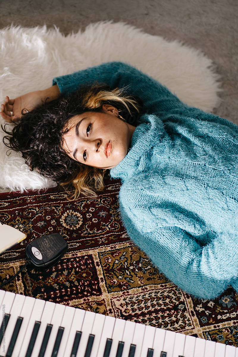 Melancholic young woman lying on floor and dreaming at home