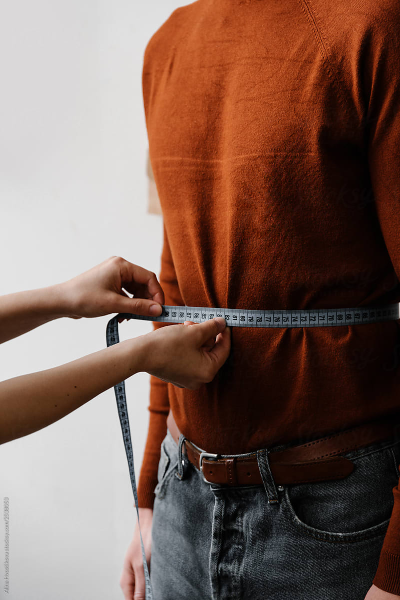 Seamstress doing measure of male waist by centimeter tape
