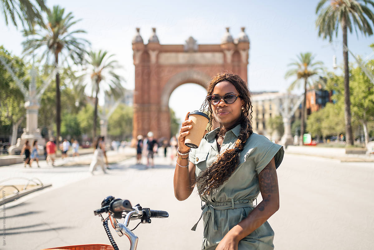 Confident black woman drinking coffee while on street