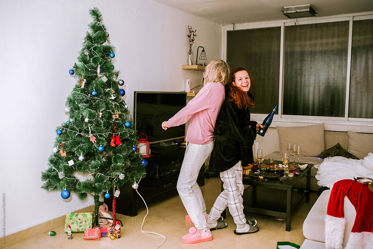 Girlfriends Laughing Near Christmas Tree with Champagne, Pajama Party.