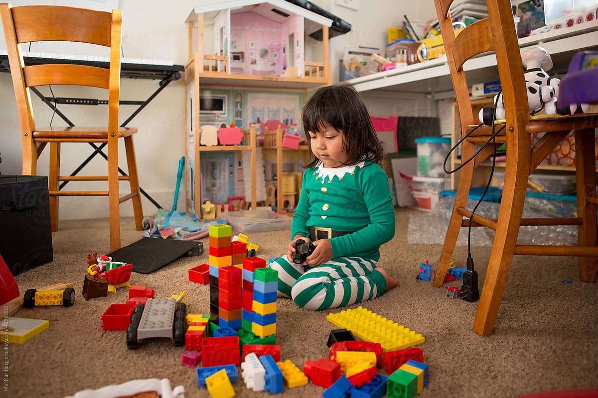 Girl in Christmas pajamas surrounded by playroom toys 2