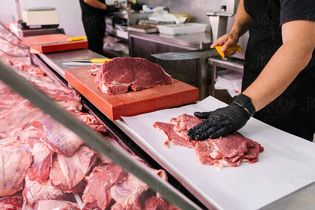 Crop butcher cutting raw meat on board