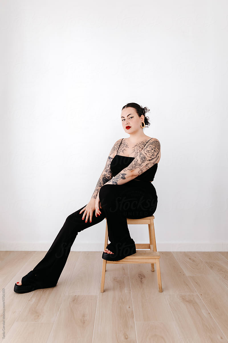 Tattooed woman on chair in studio