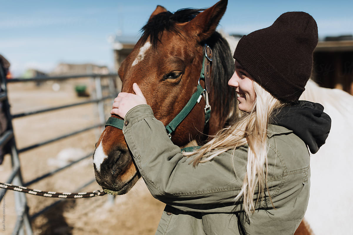 A Cowgirl Smiles and Pets Her Horse