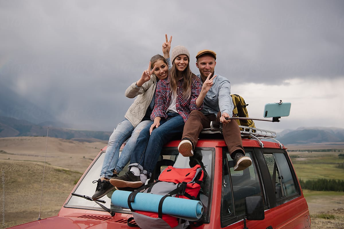Travelers posing for selfie on car