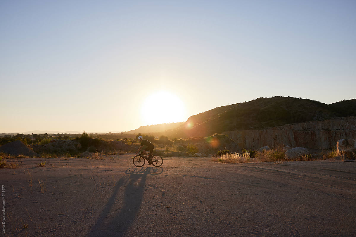 Man riding bicycle at sunset in nature