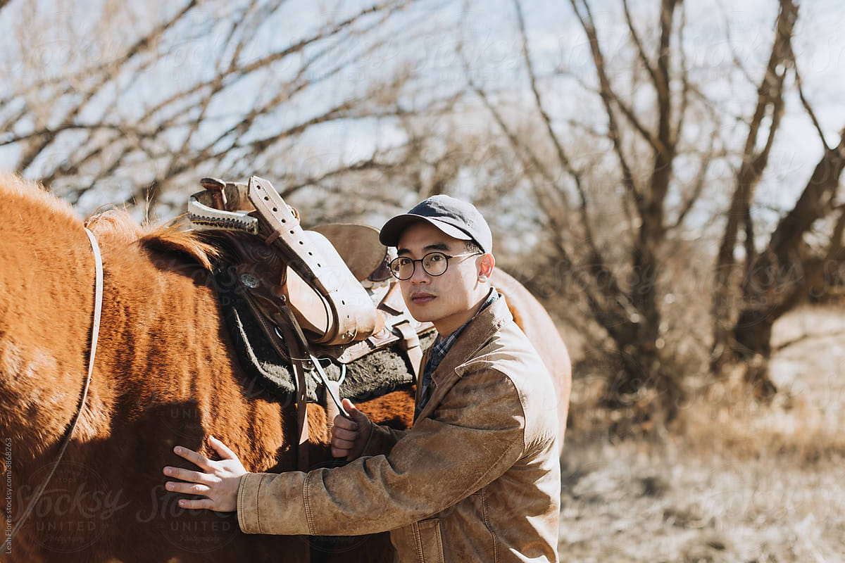 A Handsome Asian Man Stands with his Horse