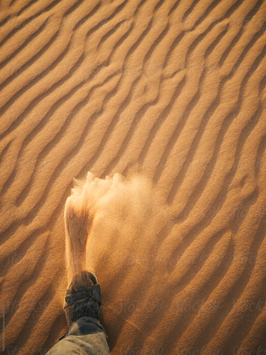 Sand flying out from a sandal in the desert