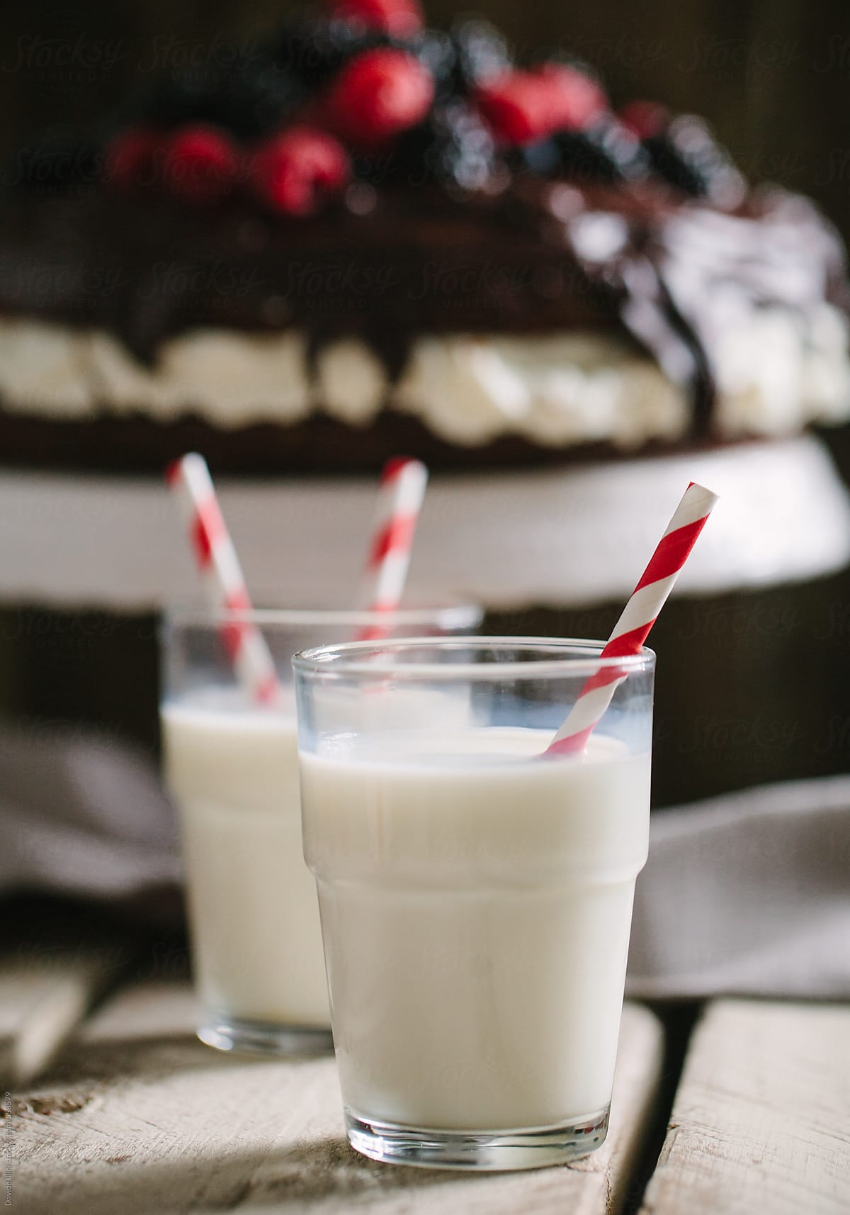 Two glass of milk with striped straws standing on old table