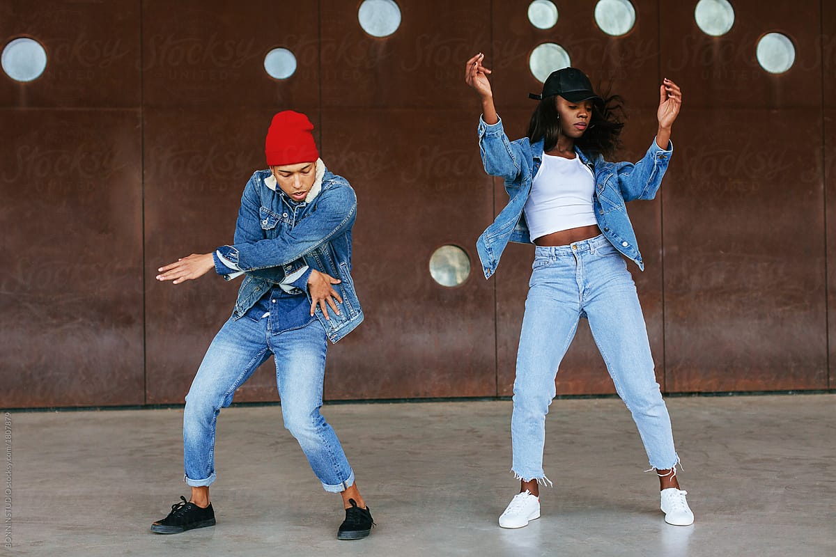 Portrait of cool couple wearing denim clothes dancing on the street.
