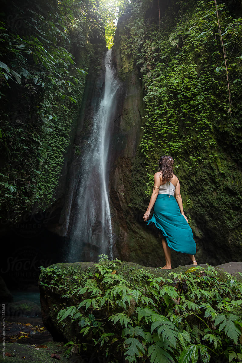 Woman Standing in Front of Waterfall in Skirt