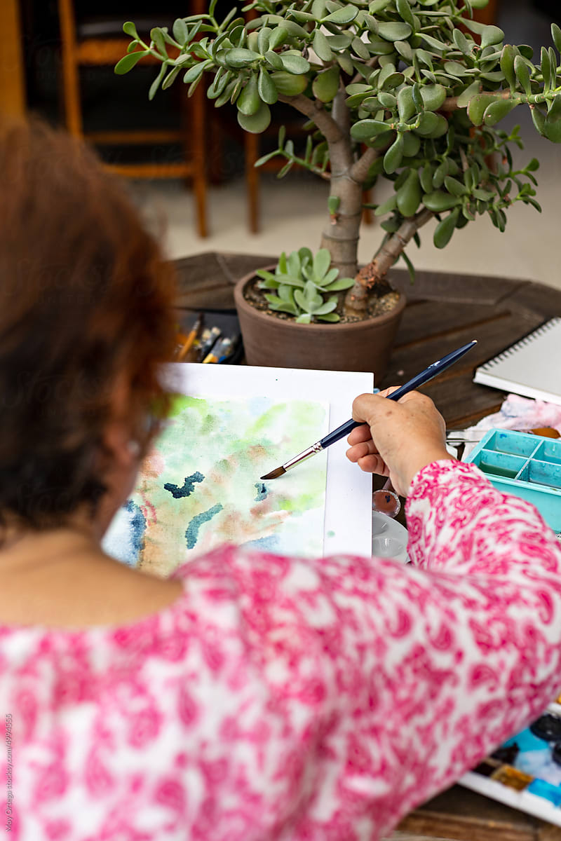 Unidentified elderly woman making watercolor strokes with brush