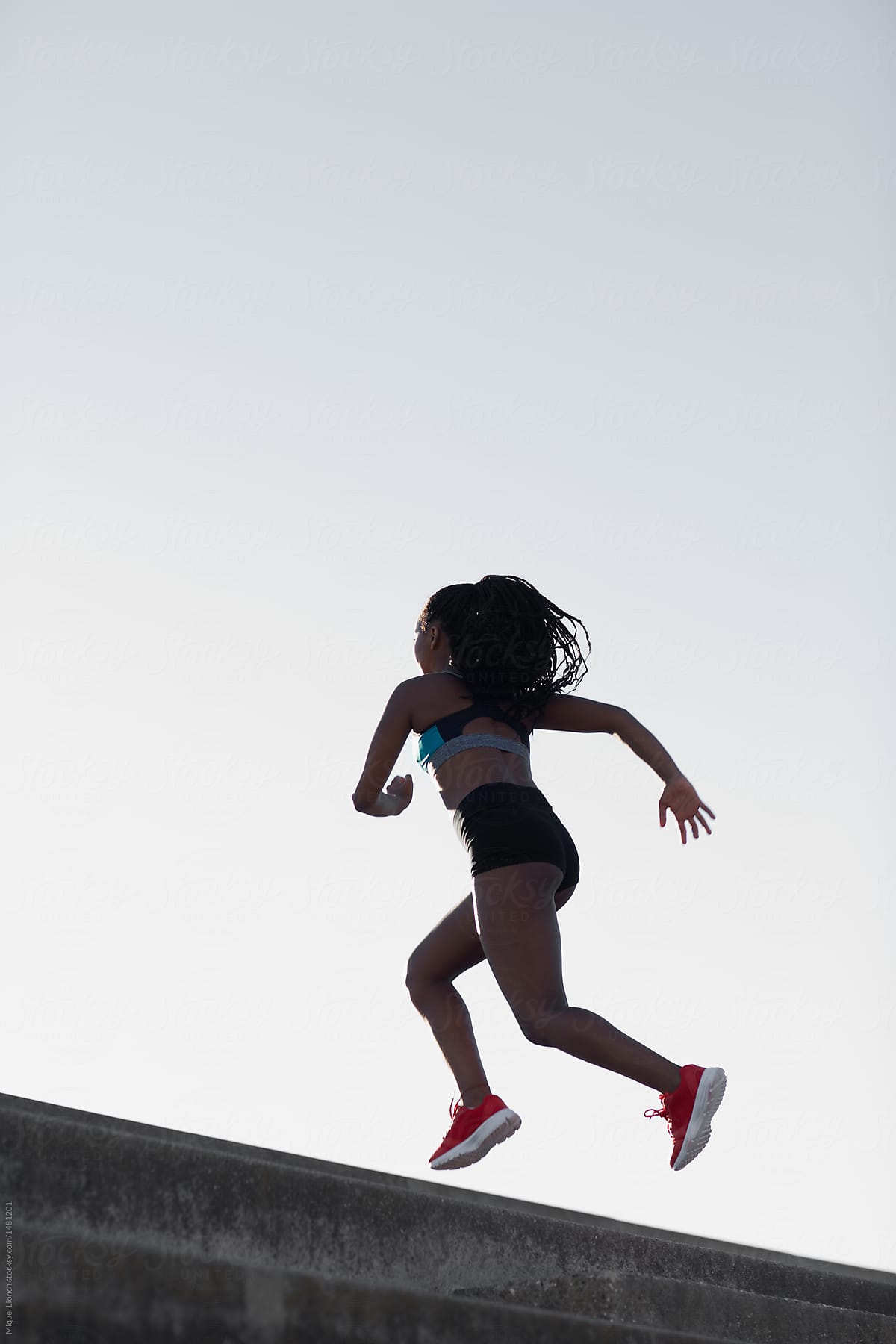 Sportswoman running against cloudless sky