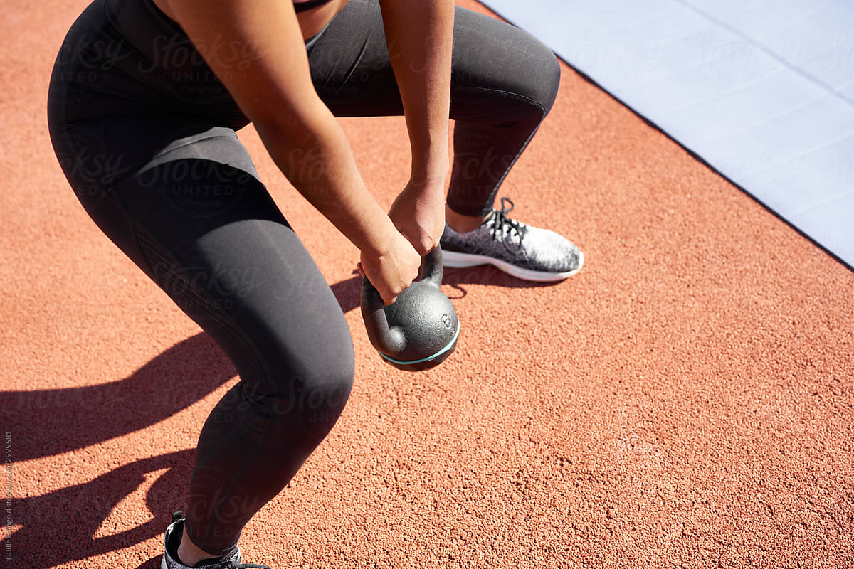 Woman exercising with kettlebell at stadium