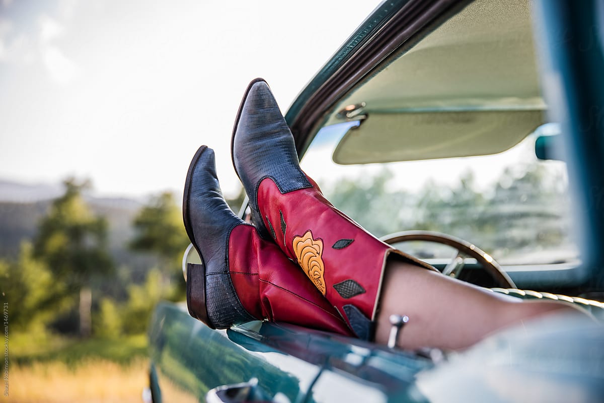 cowboy boots hanging out the window of a classic car