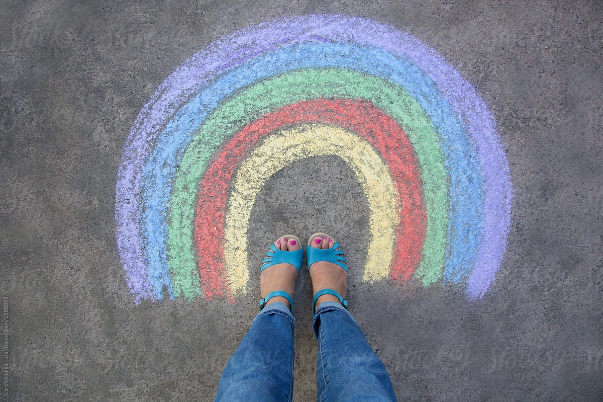 Feet in sandals inside a chalk rainbow