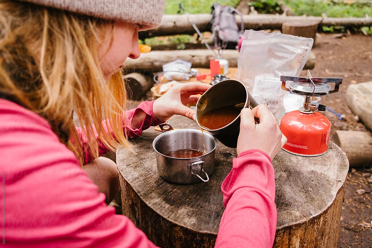 A woman pours coffee while camping