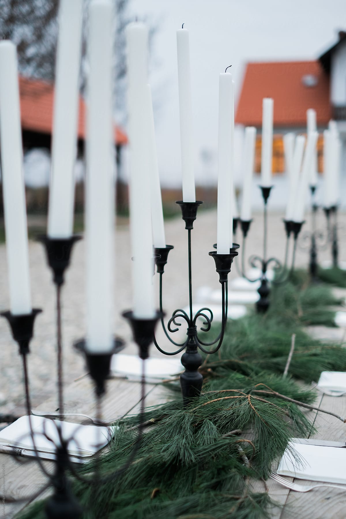 Outdoor table set-up for an outdoor meal with candles and pine branches