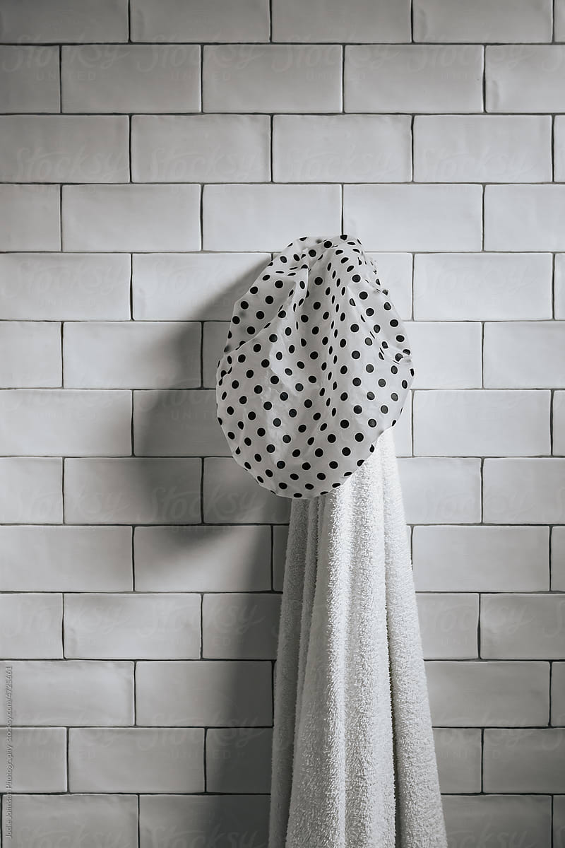 Shower cap and bath towel hanging on a wall
