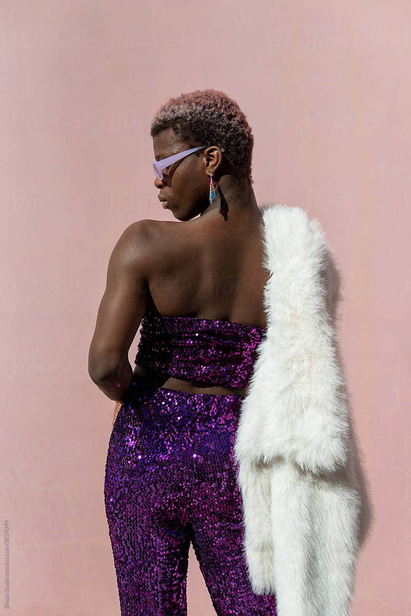 Transgender woman with sequined suit, white coat and sunglasses