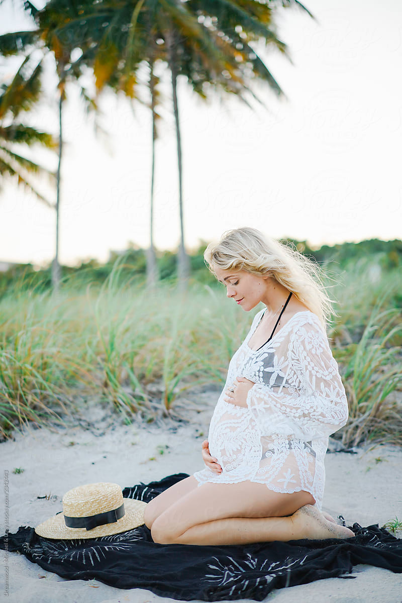 Pregnant lady in lace blouse touching tummy