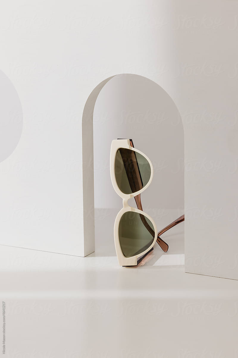 pair of sunglasses sitting in arch frame cutout of white prop wall