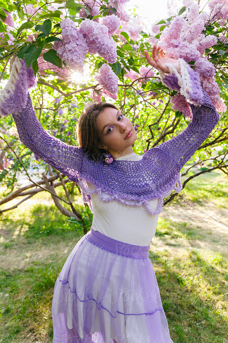 Charming woman with flowers in lilac tree park