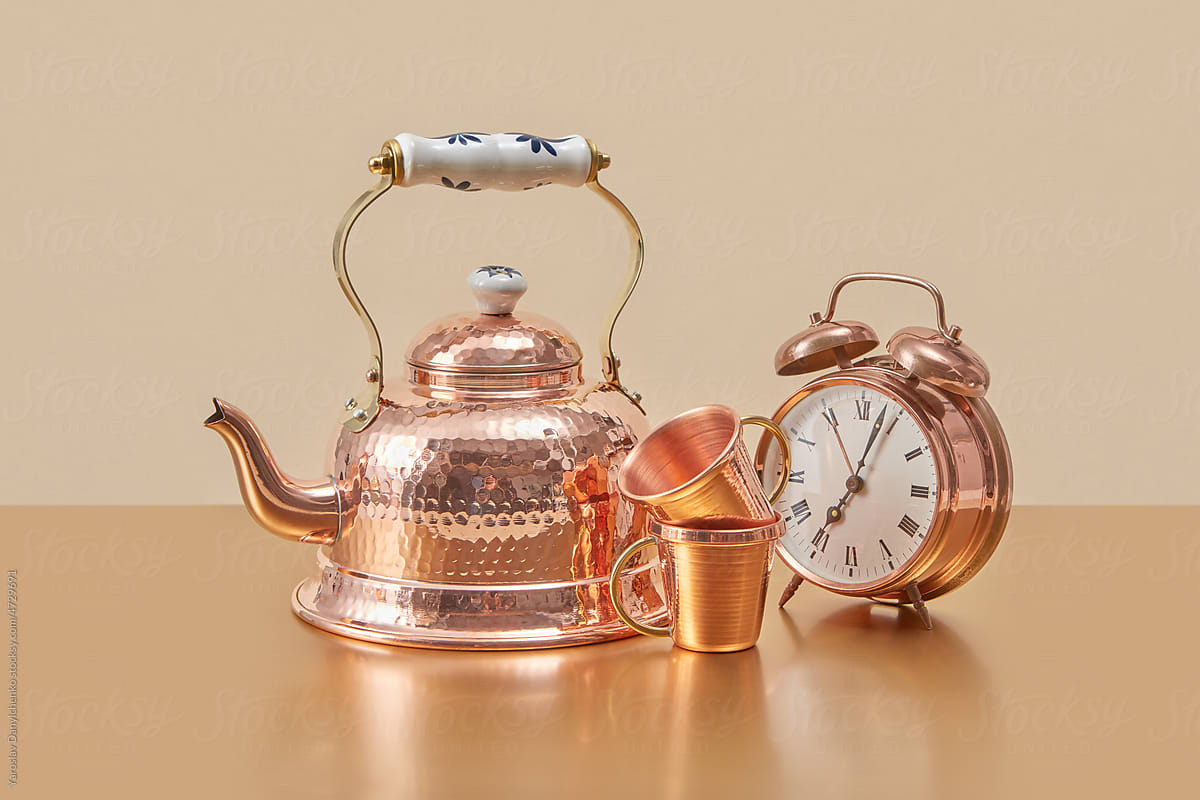 Old-fashioned copper kettle, cups and alarm clock.