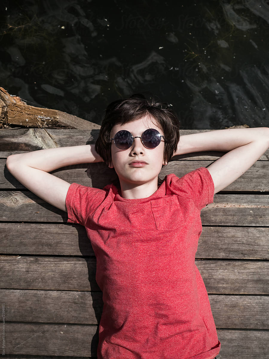 Portrait Of A Teenager Boy In Round Sunglasses by Stocksy