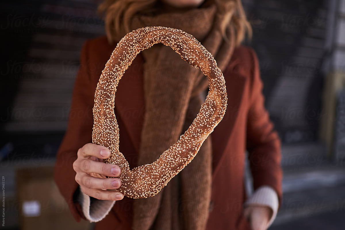 Crunchy sesame bread ring in hand of woman