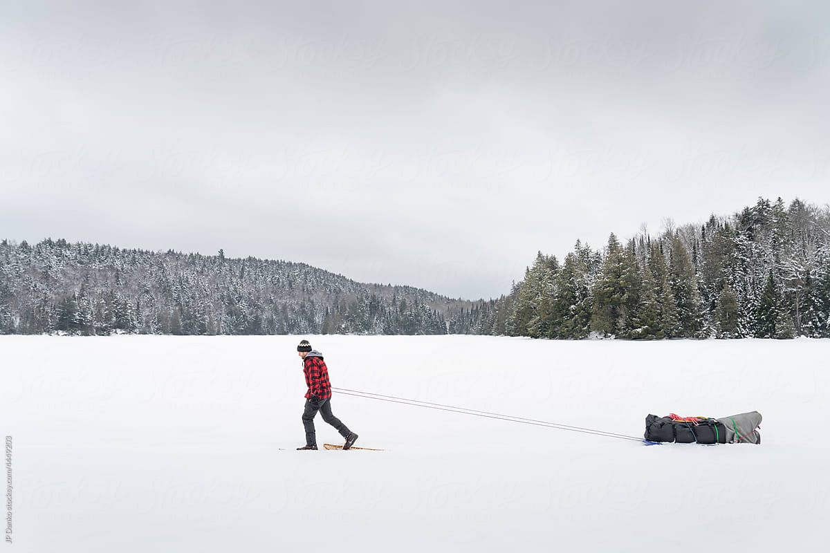 Snowshoeing with Heavy Winter Camping Sled on Frozen Lake