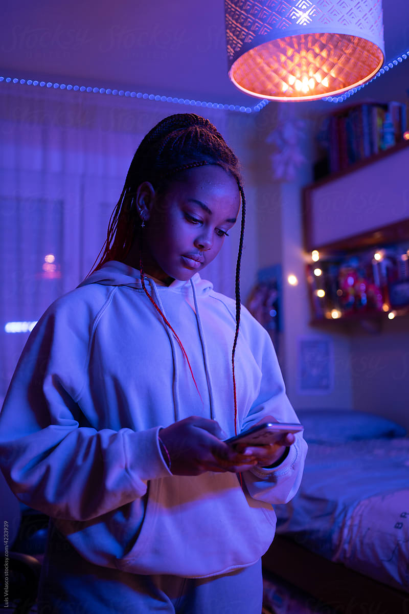 Teen Black Girl With Phone In Her Bedroom At Night.