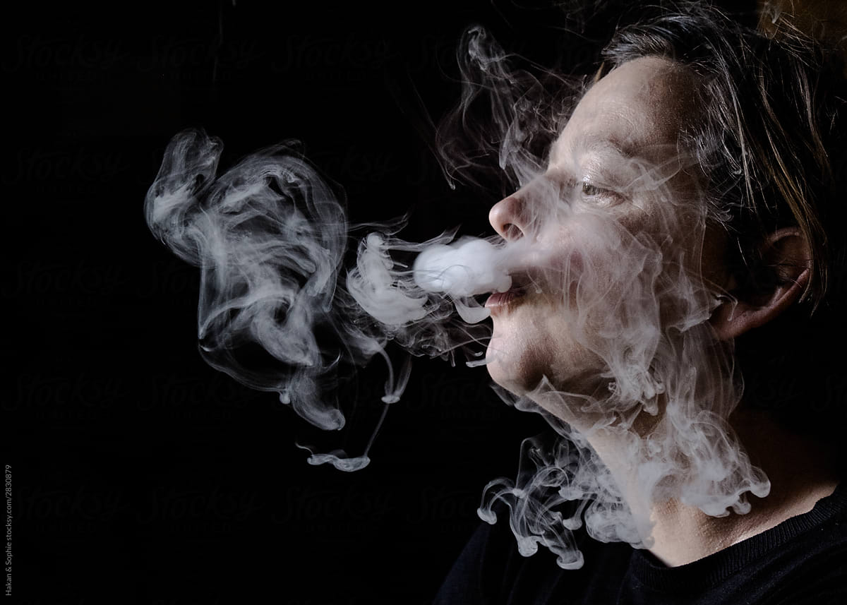 Profile of woman exhaling intricate lace like patterns of smoke
