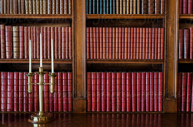 Books organized on old library shelf with antique candlestick