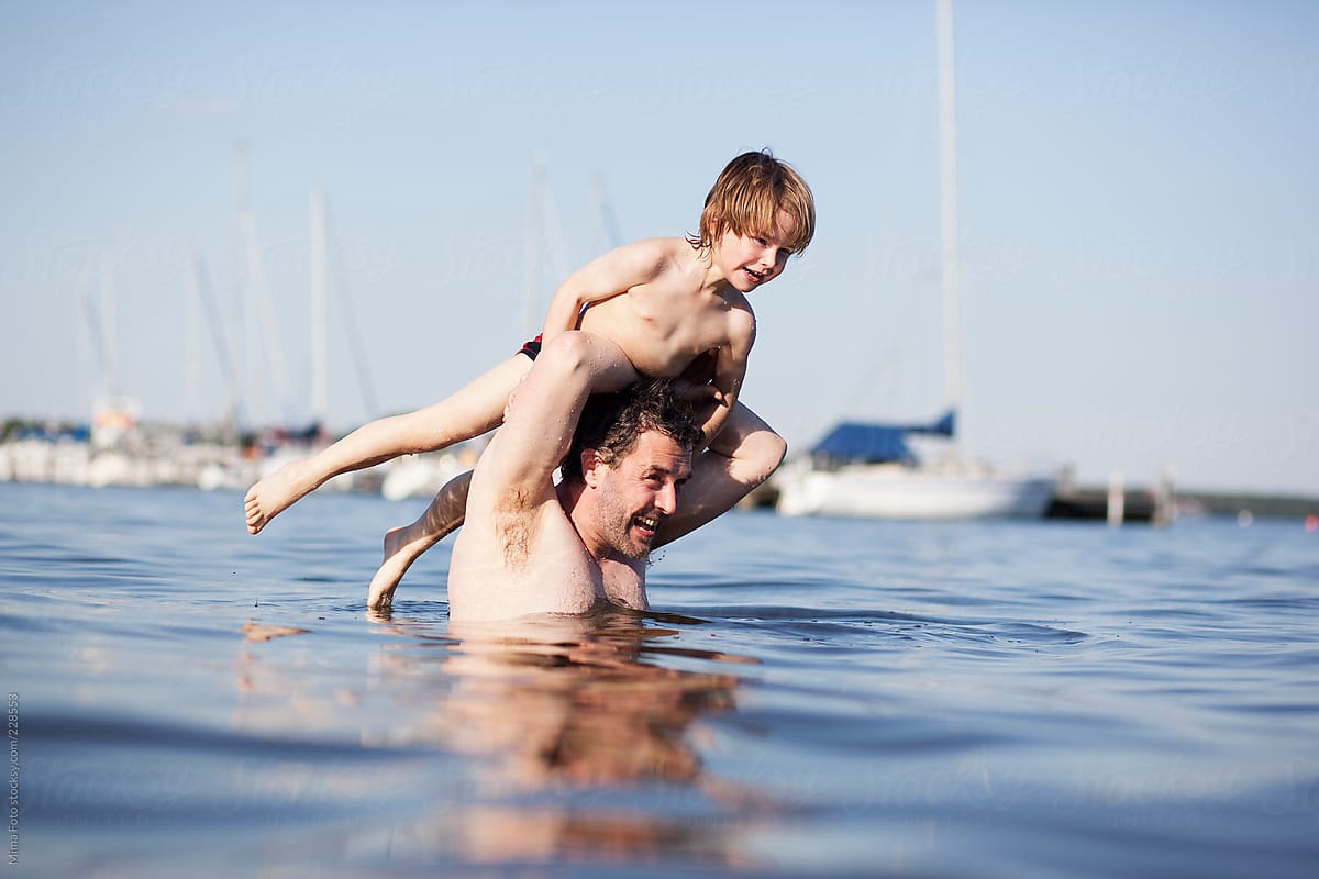 Father raising preschooler out of the water