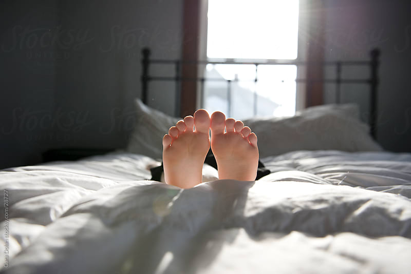 Kid feet laying down on the bed by Cara Dolan - Stocksy United