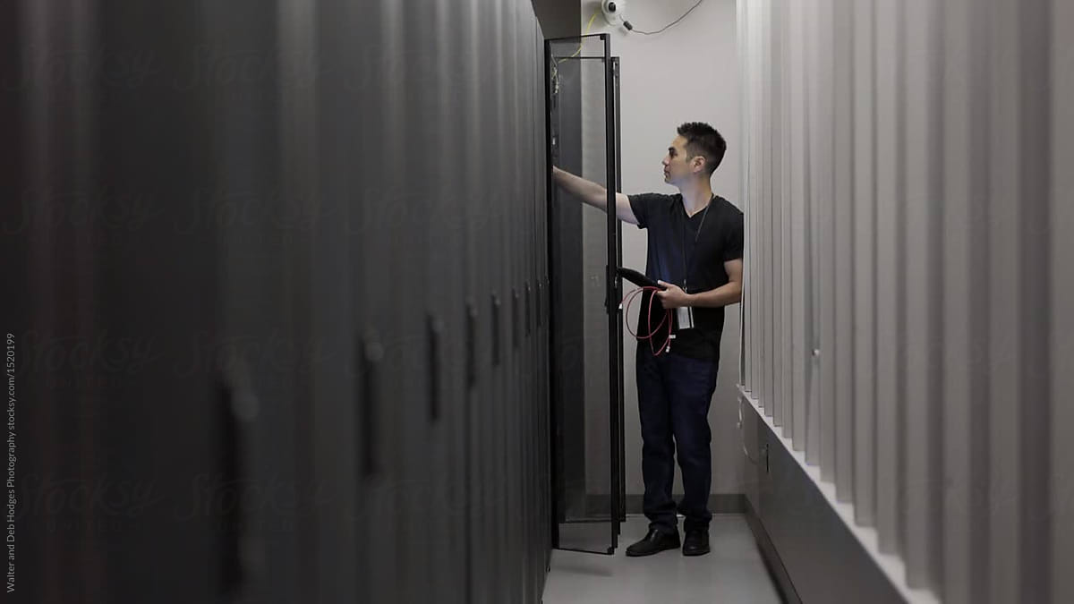  technician making adjustments to a server panel in server room by