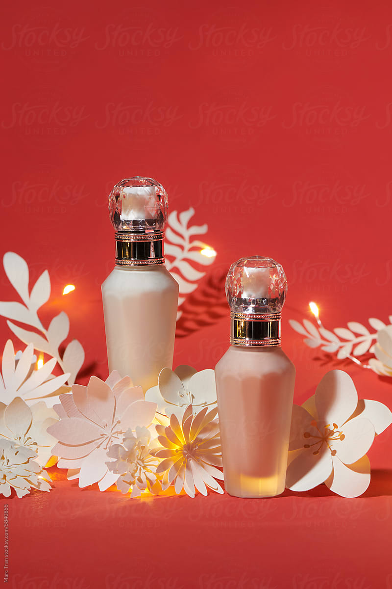 Skincare pump bottles ads with white paper flowers on red background