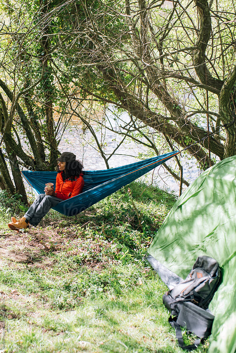 black woman in hammock at campsite with tent