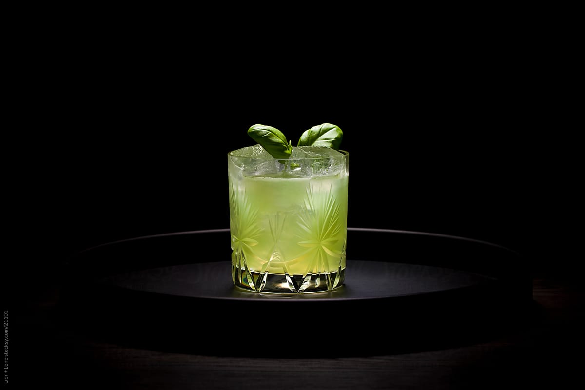 Green cocktail on round dark tray